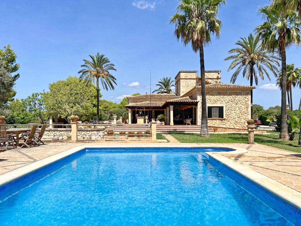 Weitläufige Außenansicht des Anwesens mit großem Pool, Terrasse und dem traditionellen Steinhaus im Hintergrund.