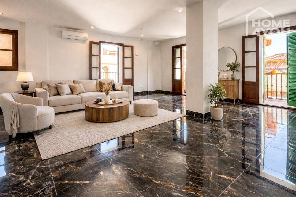 Modern eingerichtetes Wohnzimmer mit beigem Sofa, rundem Couchtisch und dunklem Marmorboden.