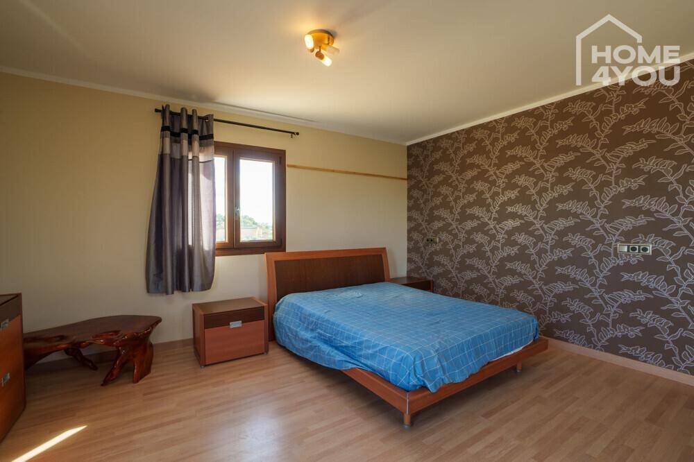 Gemütliches Schlafzimmer mit Doppelbett, Holzmöbeln und dekorativer Tapete an einer Wand.