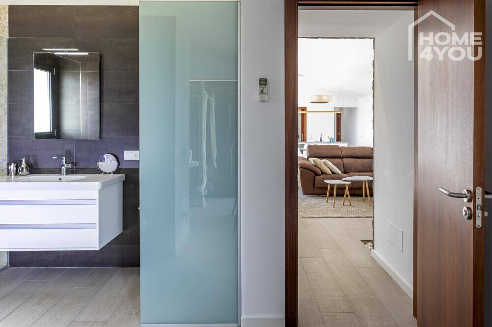 Flur mit Blick auf das Badezimmer und den offenen Wohnbereich, mit Holztür.