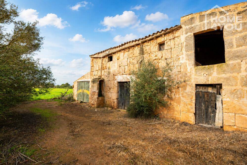 Detailansicht des alten Bauernhauses mit verwitterten Steinmauern und Holztüren in ländlicher Umgebung.