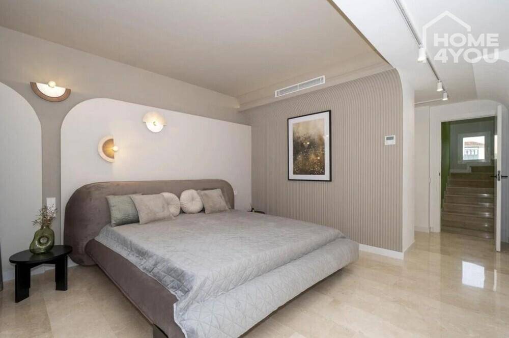 Elegantes Schlafzimmer mit großem Bett, stilvoller Wandgestaltung und Steinboden.