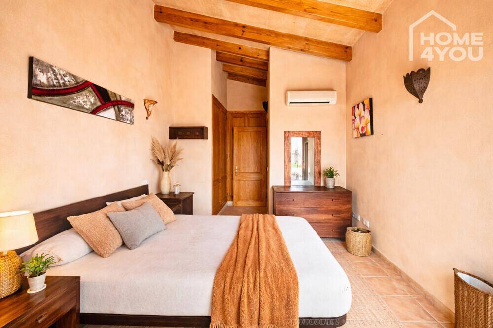 Gemütliches Schlafzimmer mit Holzbalkendecke, Fliesenboden und traditioneller Einrichtung.