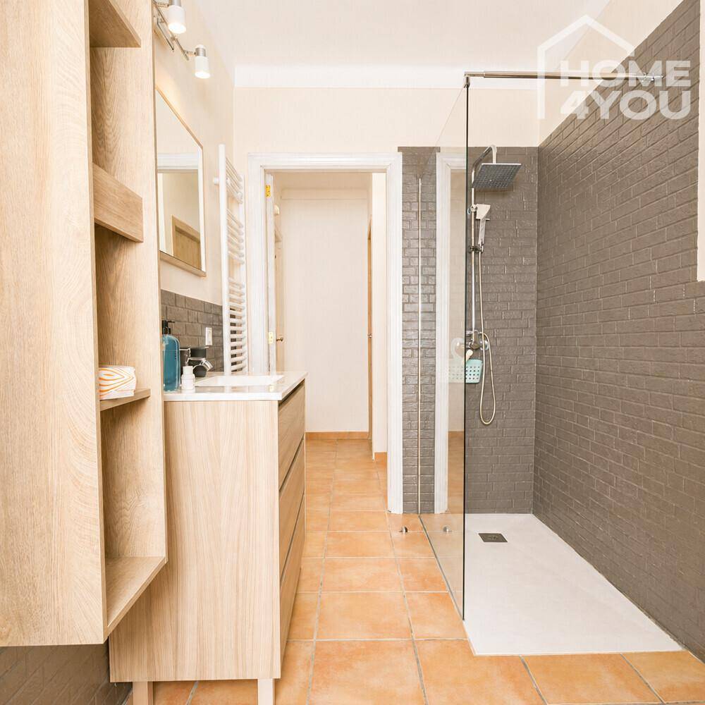 Modernes Badezimmer mit begehbarer Dusche, Holzwaschtisch und dunklen Fliesen.