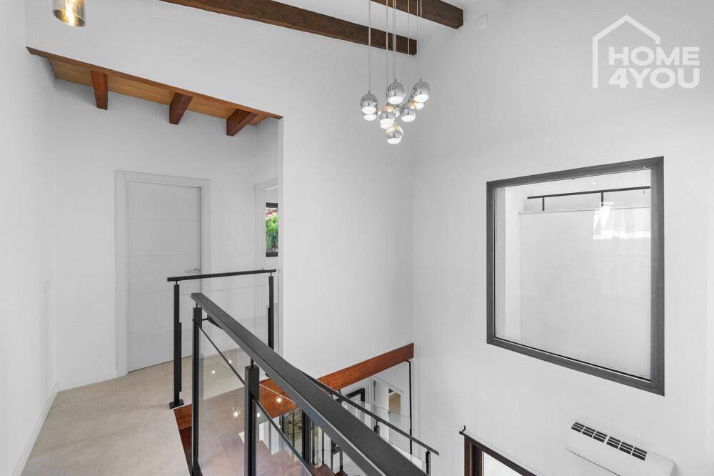 Heller Flur mit moderner Treppe, hohen Decken und eleganter Hängelampe, sehr geräumig.