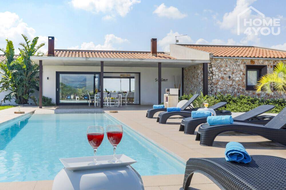 Entspannender Poolbereich mit Liegestühlen und Blick auf die moderne Villa und die Landschaft.