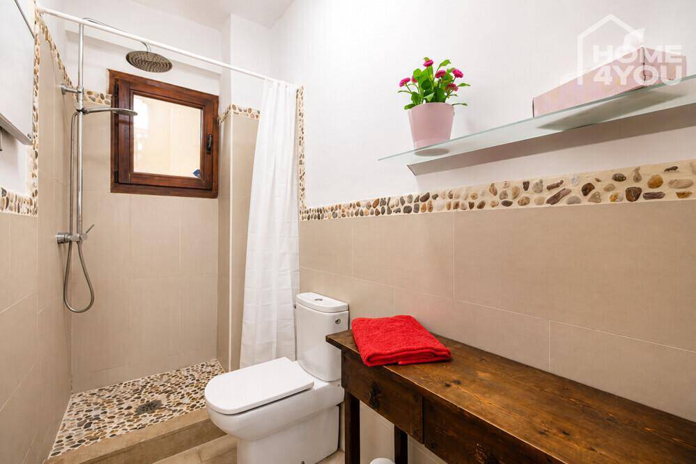 Badezimmer mit begehbarer Dusche, WC und dekorativen Kieselsteinen.