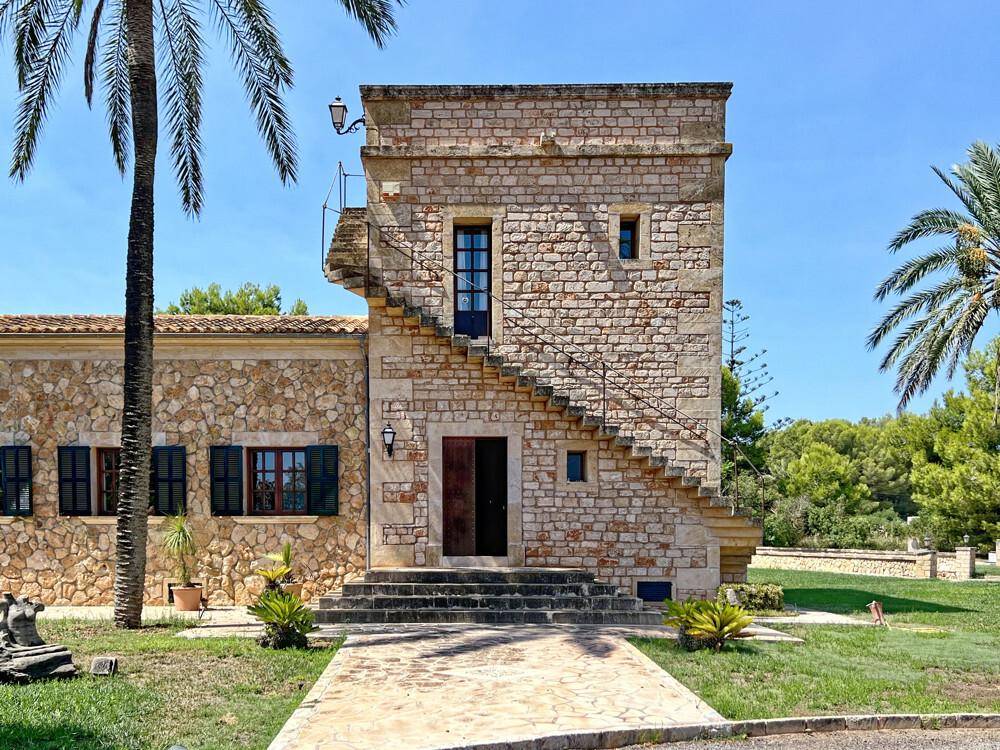 Detailansicht des Steinhauses mit Außentreppe, Holztüren und Fensterläden im mediterranen Stil.