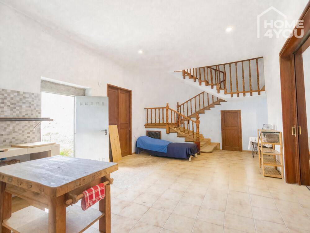 Geräumiger Bereich mit markanter Holztreppe, Fliesenboden und vorbereiteten Küchenelementen.