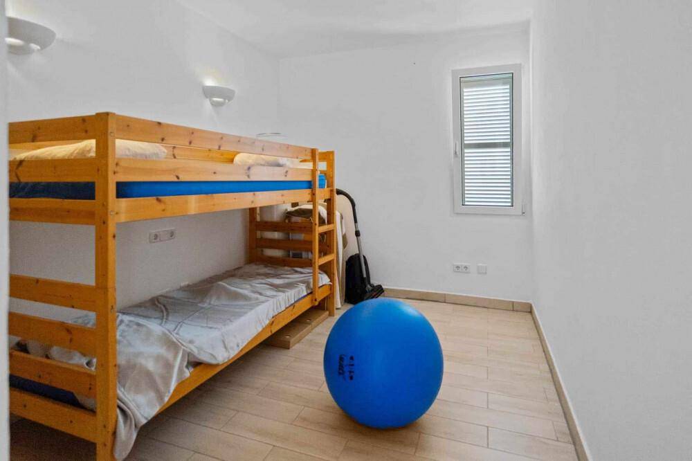 Kinderzimmer mit Etagenbett aus Holz und einem großen blauen Gymnastikball auf dem Boden.