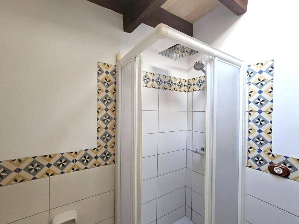 Duschkabine mit Regenduschkopf und dekorativen Fliesen im traditionellen Badezimmer.
