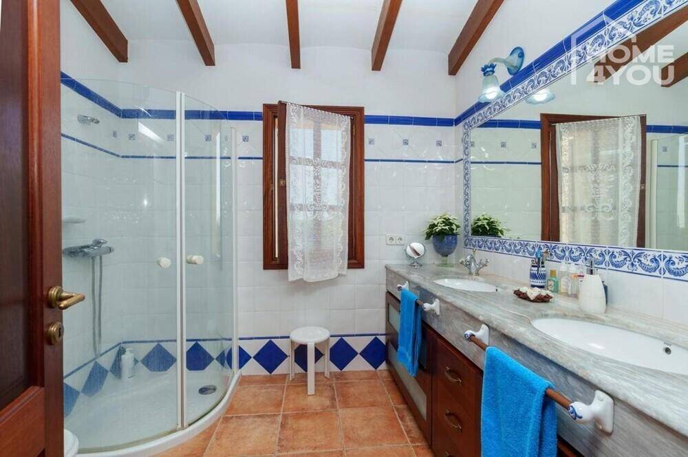Traditionelles Badezimmer mit blauen Akzentfliesen, Doppelwaschbecken und Duschkabine.