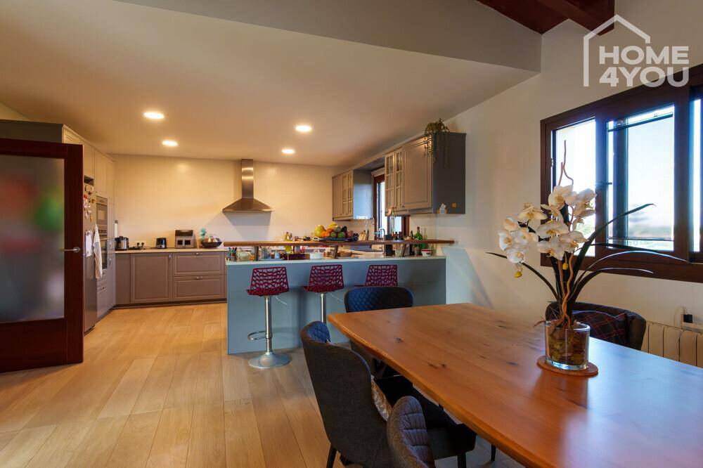 Geräumiger Essbereich mit Holztisch und offener Küche mit Insel und Barhockern.