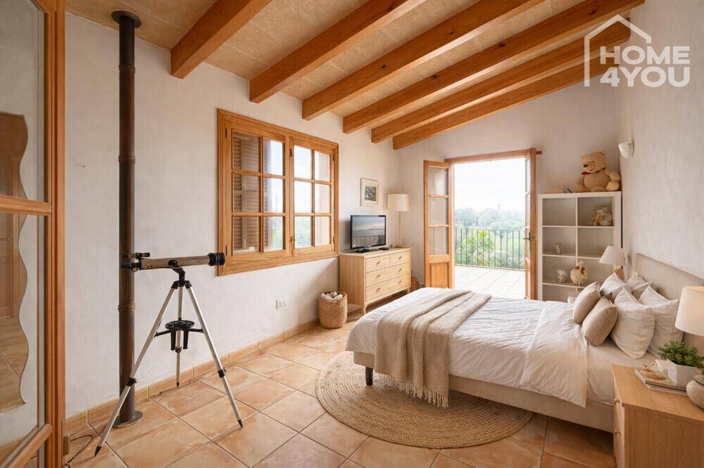 Helles Schlafzimmer mit Holzbalkendecke, Fliesenboden und Zugang zum Balkon mit schöner Aussicht.