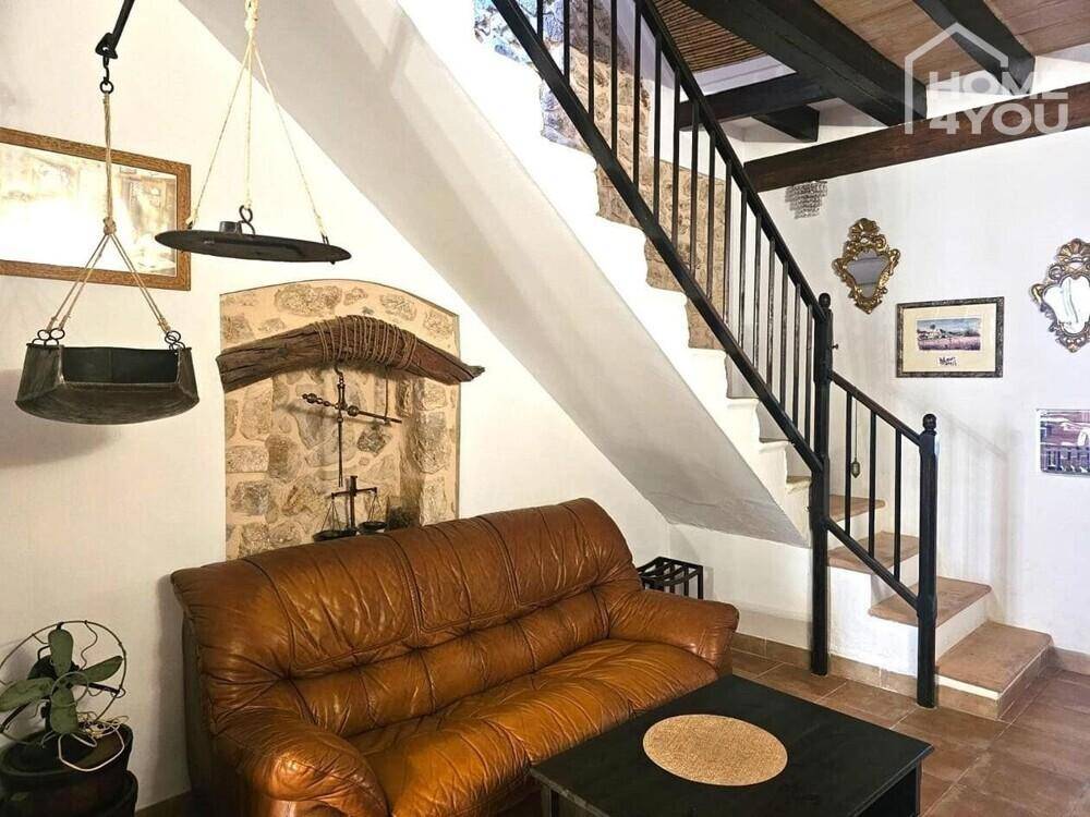 Gemütlicher Wohnbereich mit Ledersofa, Steinfliesen und einer eleganten Treppe.