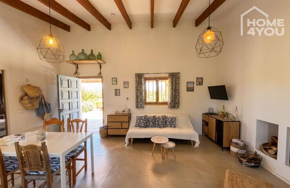 Gemütlicher Wohnbereich mit Sofa, Esstisch und rustikalen Holzbalken an der Decke.