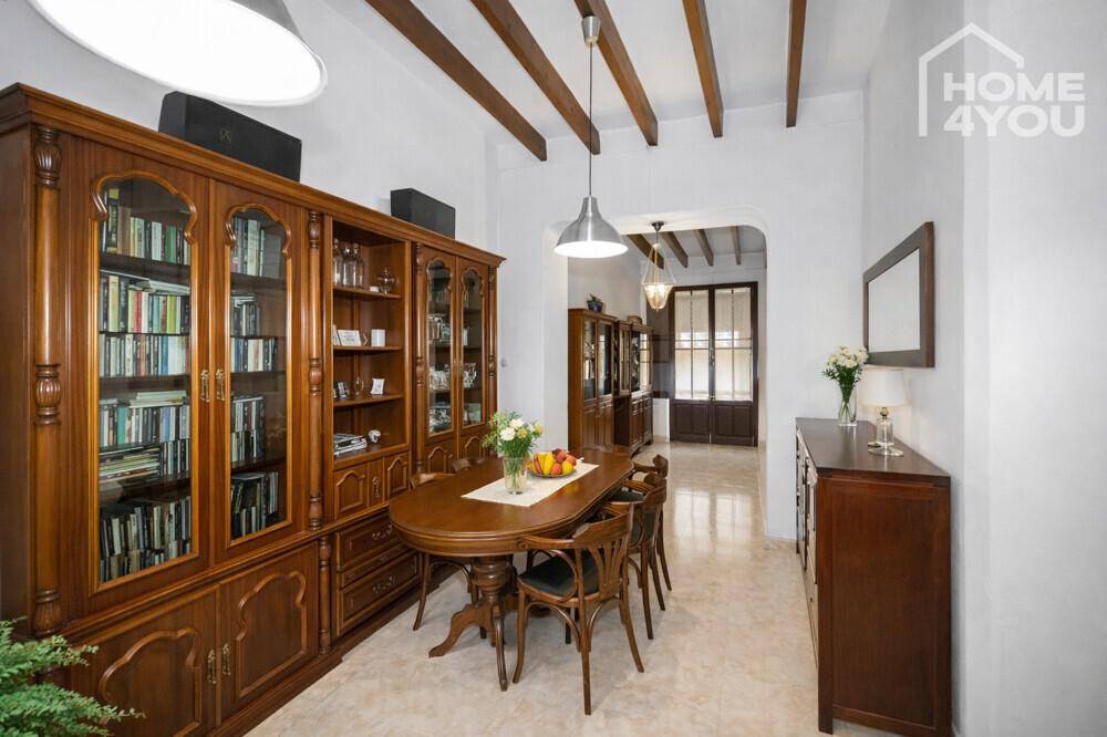 Eleganter Essbereich mit großem Holztisch, Vitrinen und sichtbaren Holzbalken an der Decke.