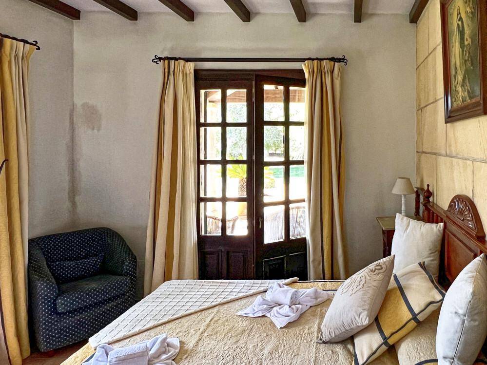 Helles Schlafzimmer mit Zugang zu einem Außenbereich und traditionellen Holzbalken.
