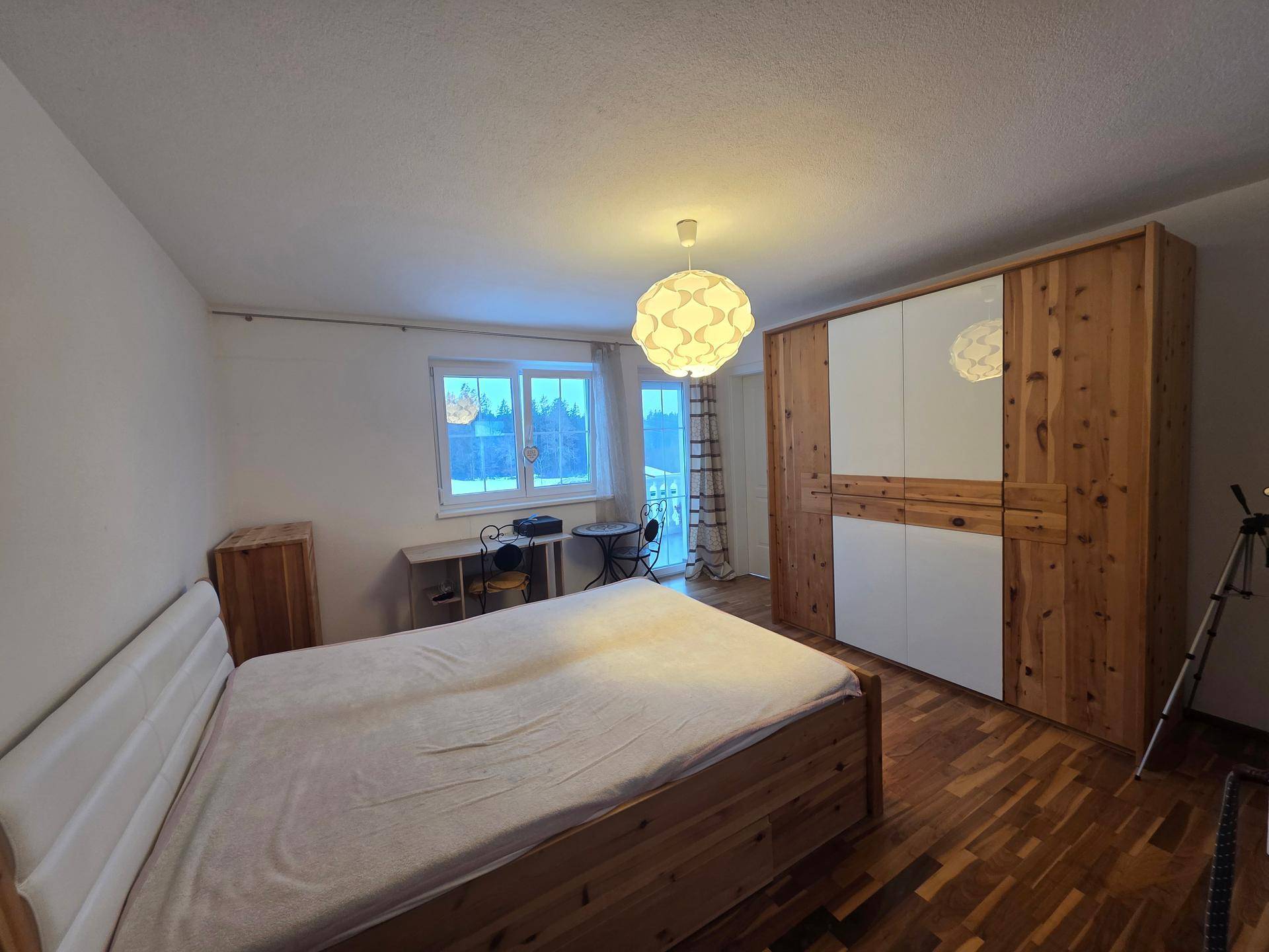 Gemütliches Schlafzimmer mit Holzbett, großem Kleiderschrank und hochwertigem Parkettboden.