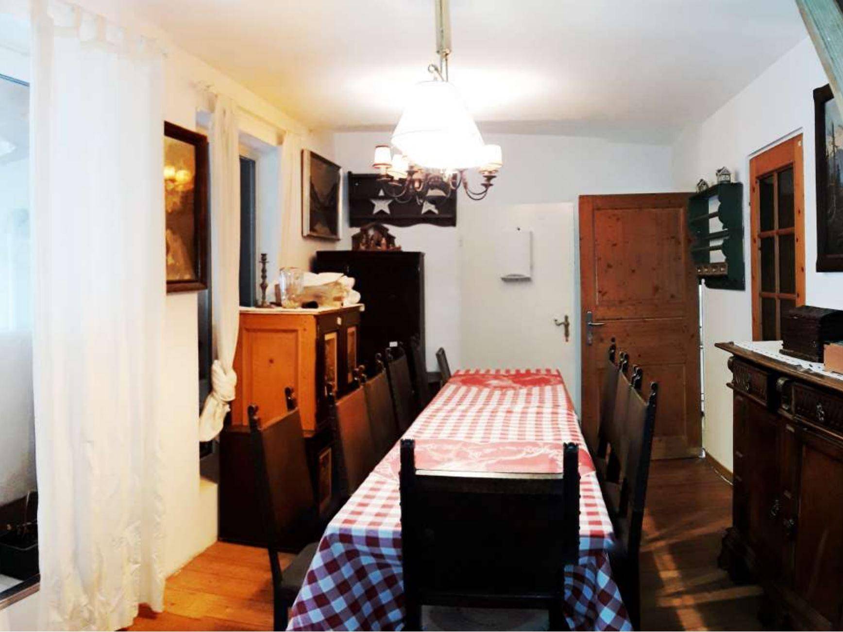 Traditioneller Essbereich mit Holztisch, karierter Tischdecke und dunklen Holzmöbeln.