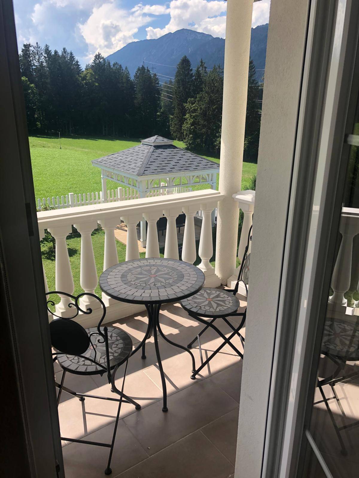 Kleiner Balkon mit Sitzgelegenheiten und malerischem Blick auf den Garten und die Berge.