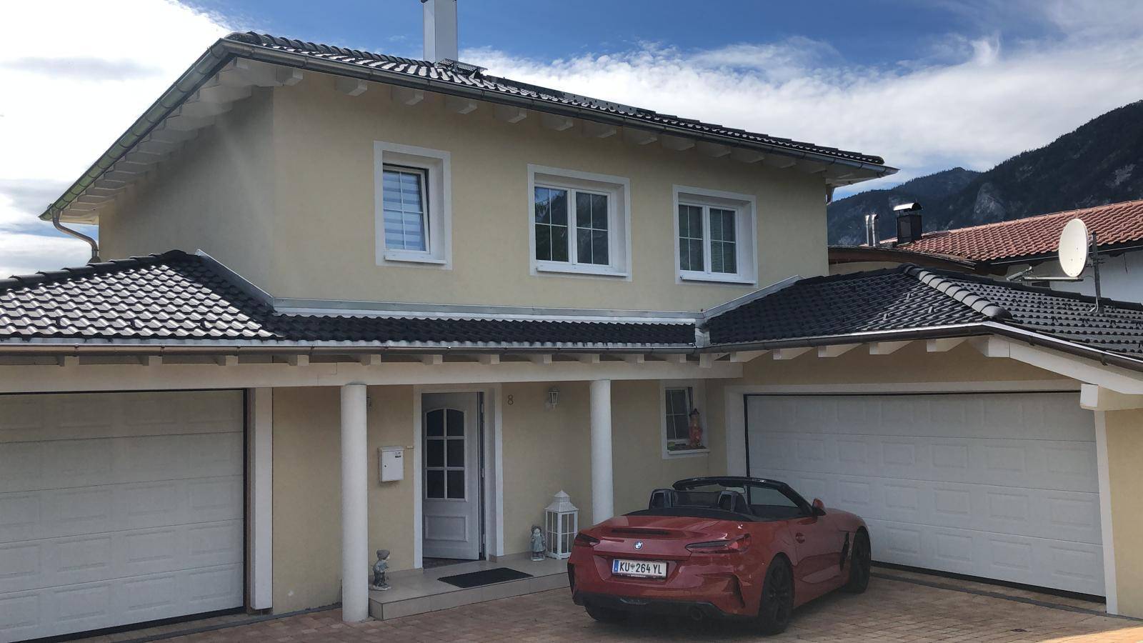 Vorderansicht eines modernen Hauses mit Doppelgarage, gepflasterter Einfahrt und Satteldach.