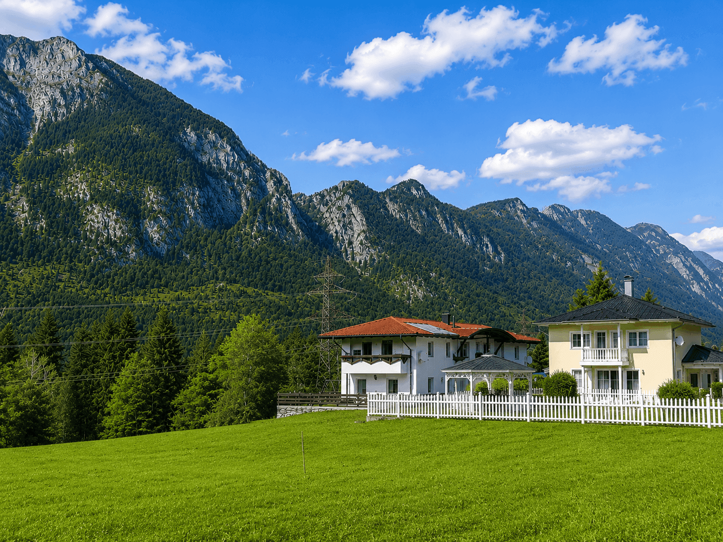 Haus in ländlicher Umgebung mit Bergblick und weitem Grünland im Vordergrund.