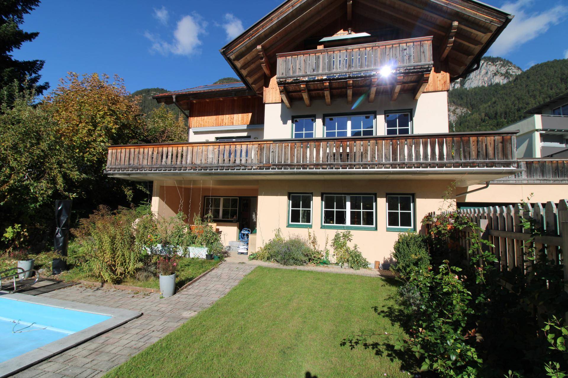 Ansicht des Hauses mit Garten, Pool und mehreren Balkonen vor alpiner Kulisse.