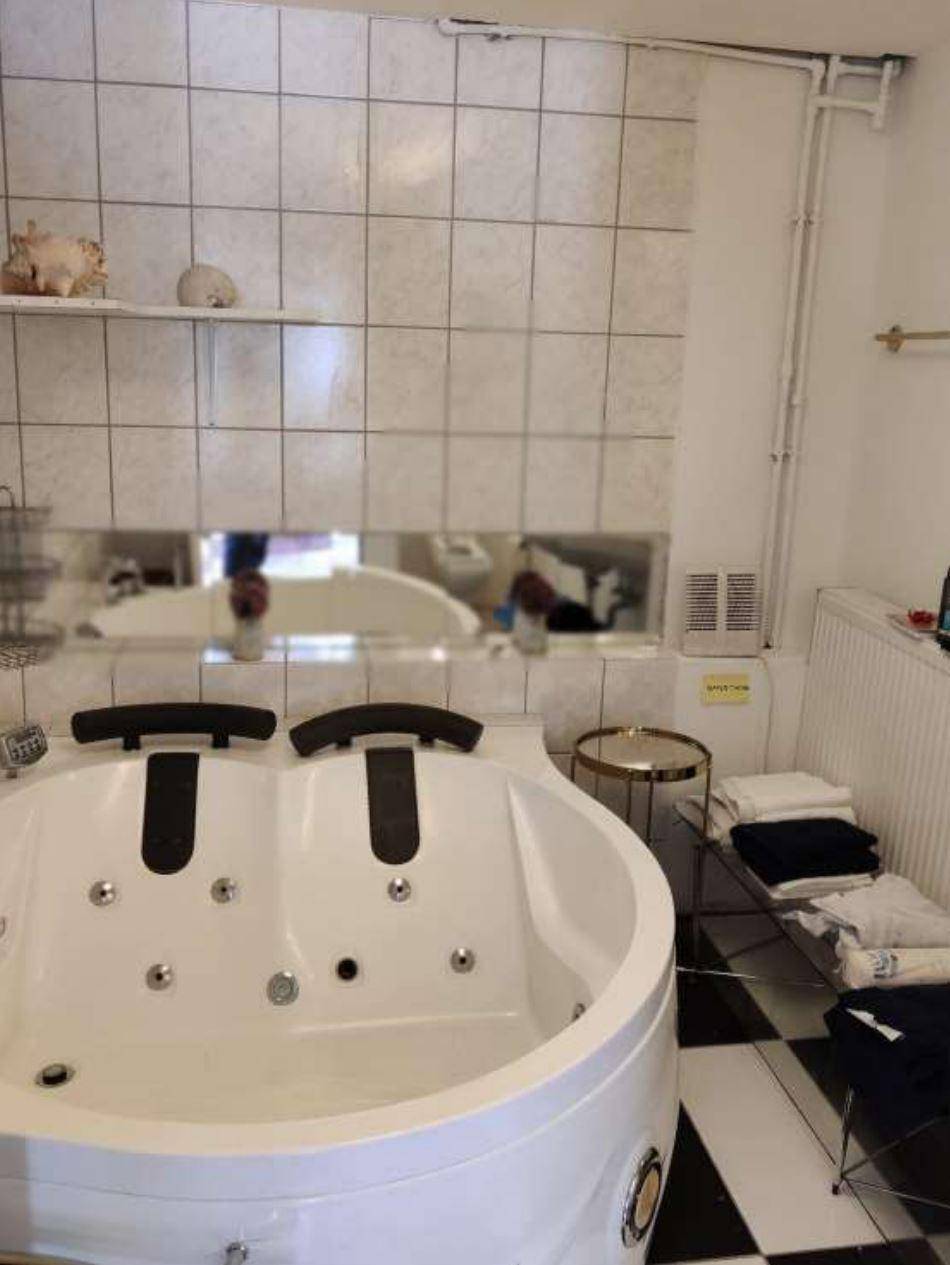 Modernes Badezimmer mit großer Whirlpool-Badewanne und schwarz-weiß gefliestem Boden.