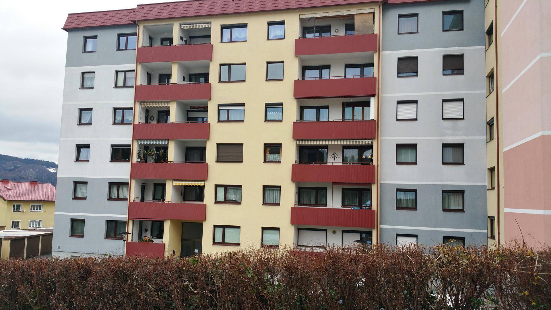 Mehrfamilienhaus mit farbiger Fassade und zahlreichen Balkonen in einer Wohngegend.