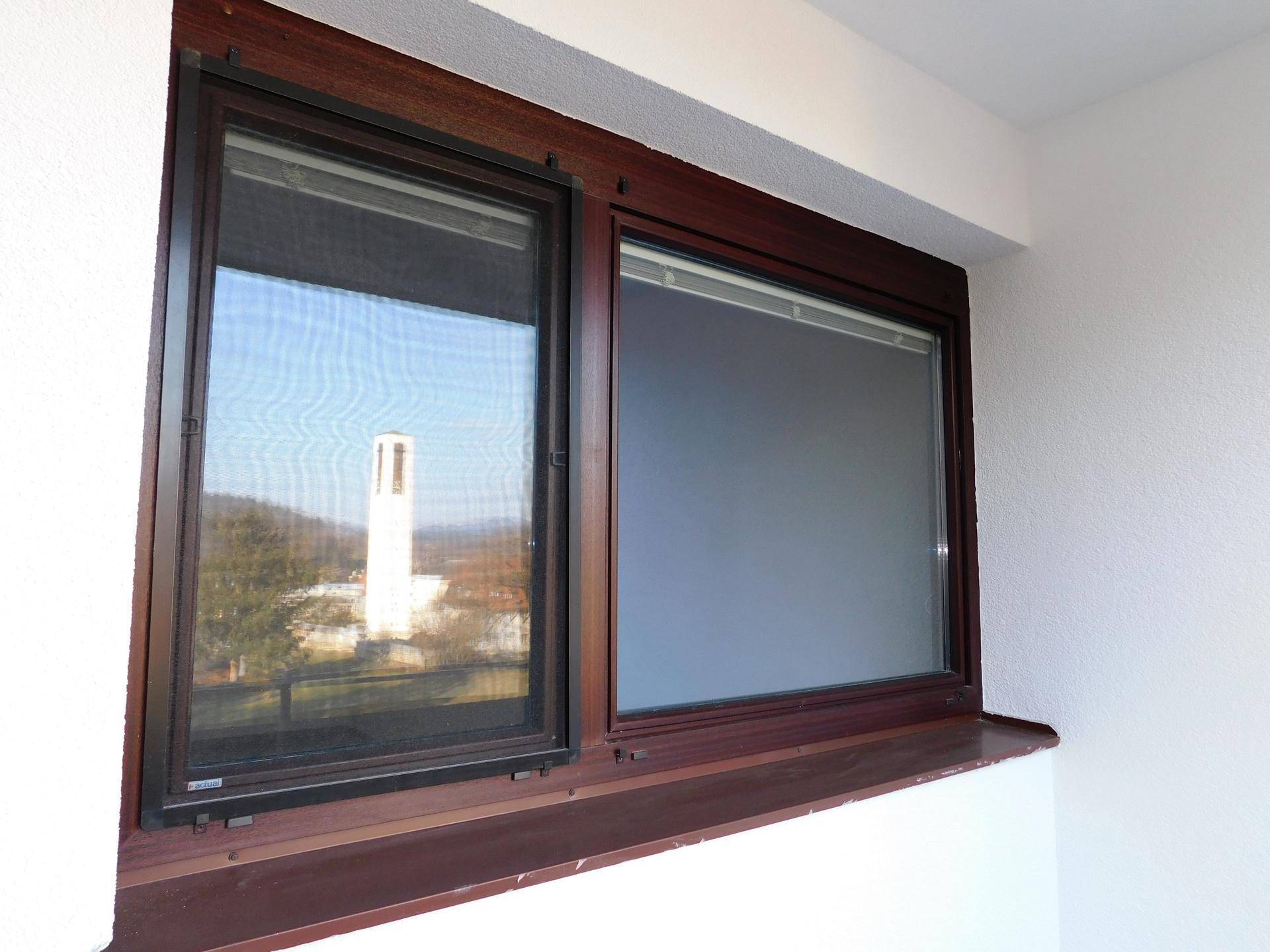 Fenster auf dem Balkon mit Blick auf einen Turm und die umliegende Landschaft.