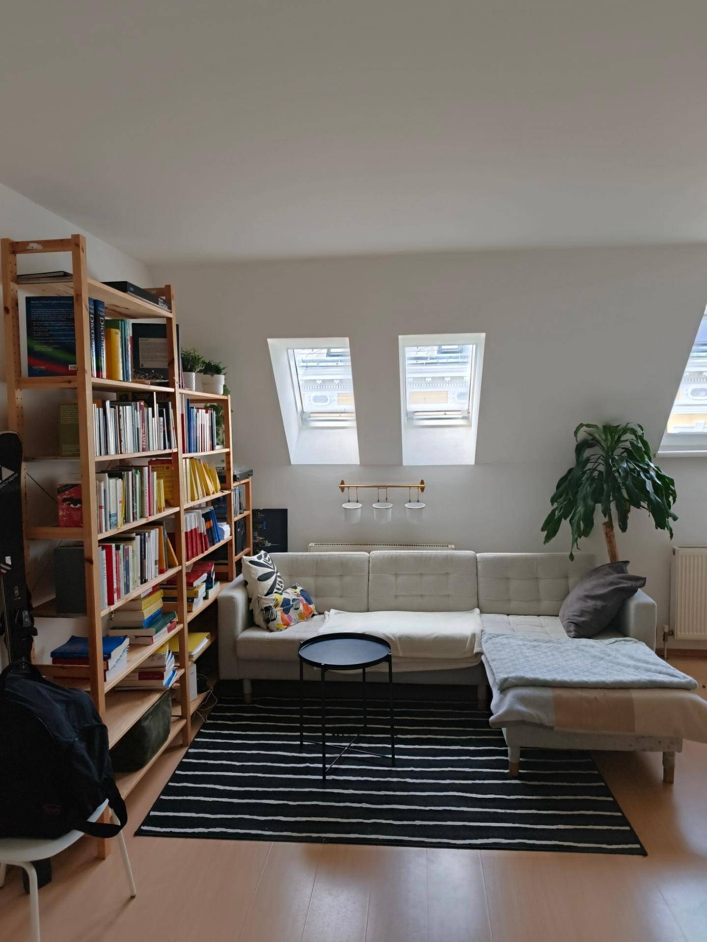 Gemütlicher Wohnbereich mit beigem Sofa, Couchtisch und einem gut gefüllten Bücherregal.
