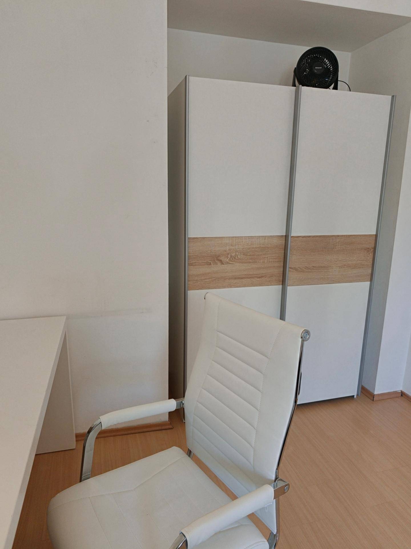 Geschlossener Kleiderschrank in einer Nische mit Schiebetüren und Holzakzenten neben dem Schreibtisch.