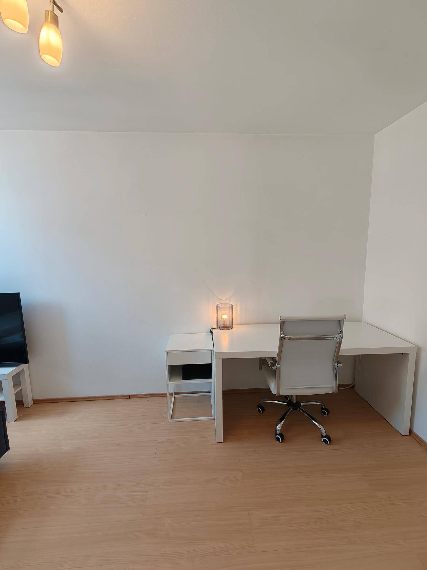 Heller Arbeitsbereich im Schlafzimmer mit weißem Schreibtisch und modernem Bürostuhl.