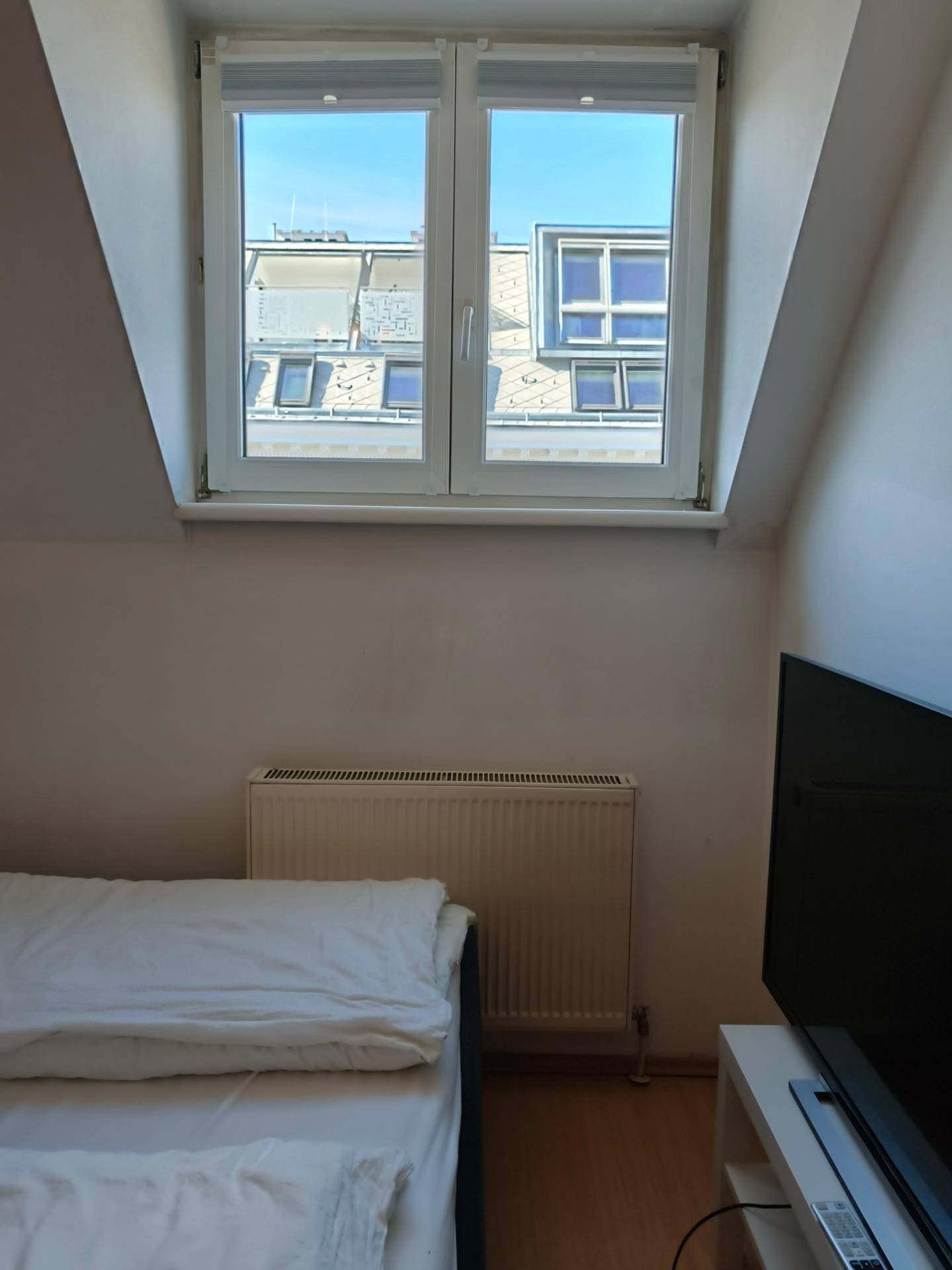Fenster im Dachgeschoss-Schlafzimmer mit Blick auf die umliegenden Dächer und den Himmel.
