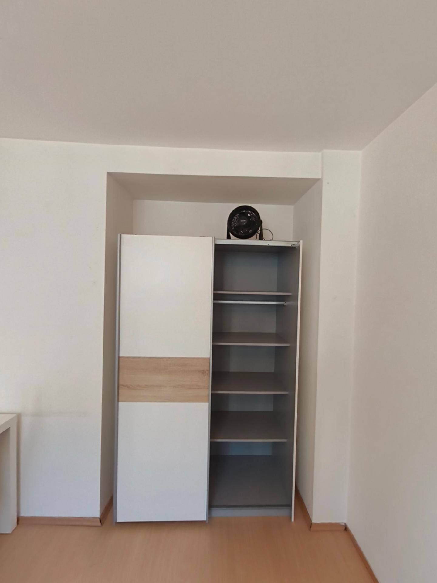 Offener Kleiderschrank in einer Nische mit Regalböden und einem Ventilator obenauf.