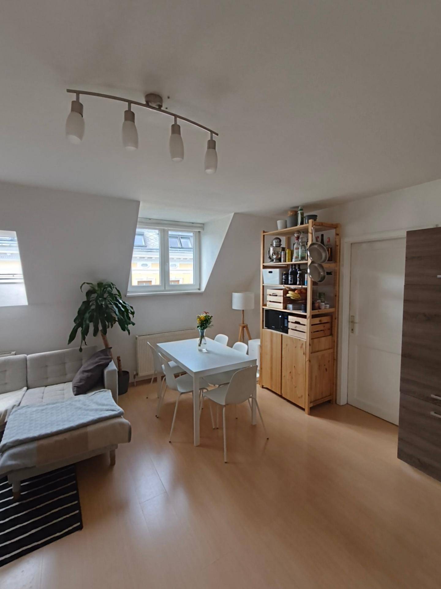 Geräumiger Wohn-Essbereich mit Sofa, Esstisch, Holzregal und Dachschräge.