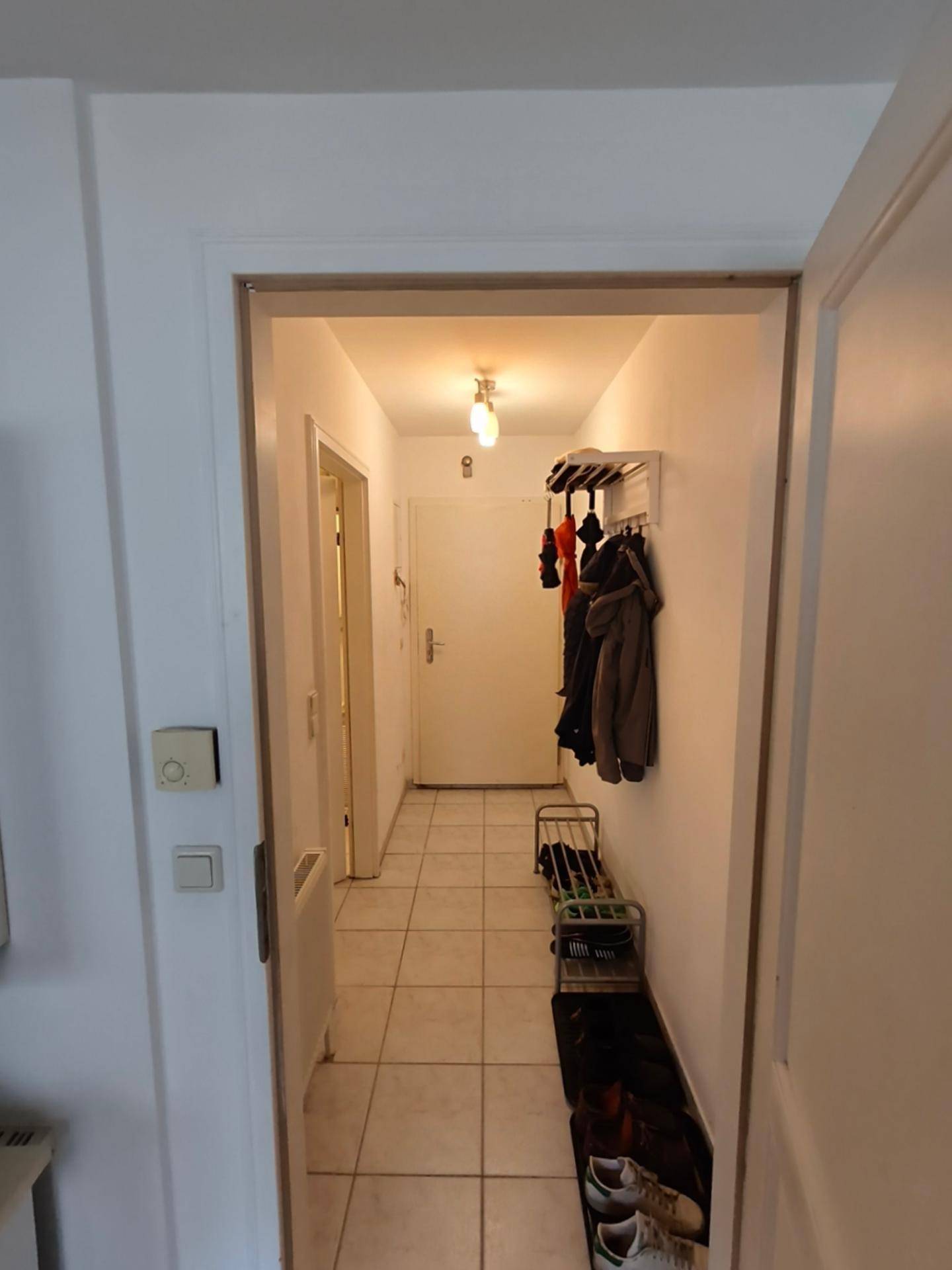 Heller Flur mit Fliesenboden, Garderobe und Schuhregal, führt zu weiteren Räumen.