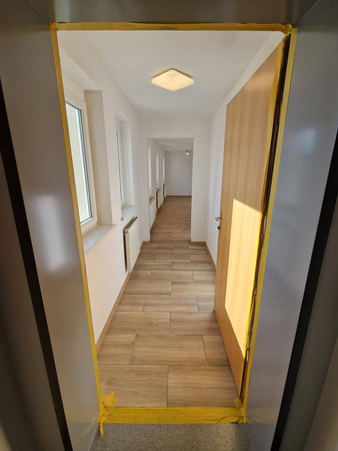 Langer, heller Flur mit Laminatboden und mehreren Fenstern, die für gute Belichtung sorgen.