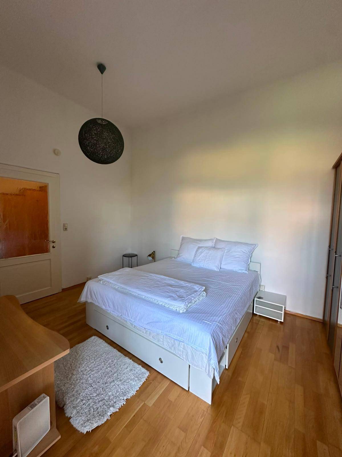 Geräumiges Schlafzimmer mit Doppelbett, Teppich und Kleiderschrank, hell und einladend.