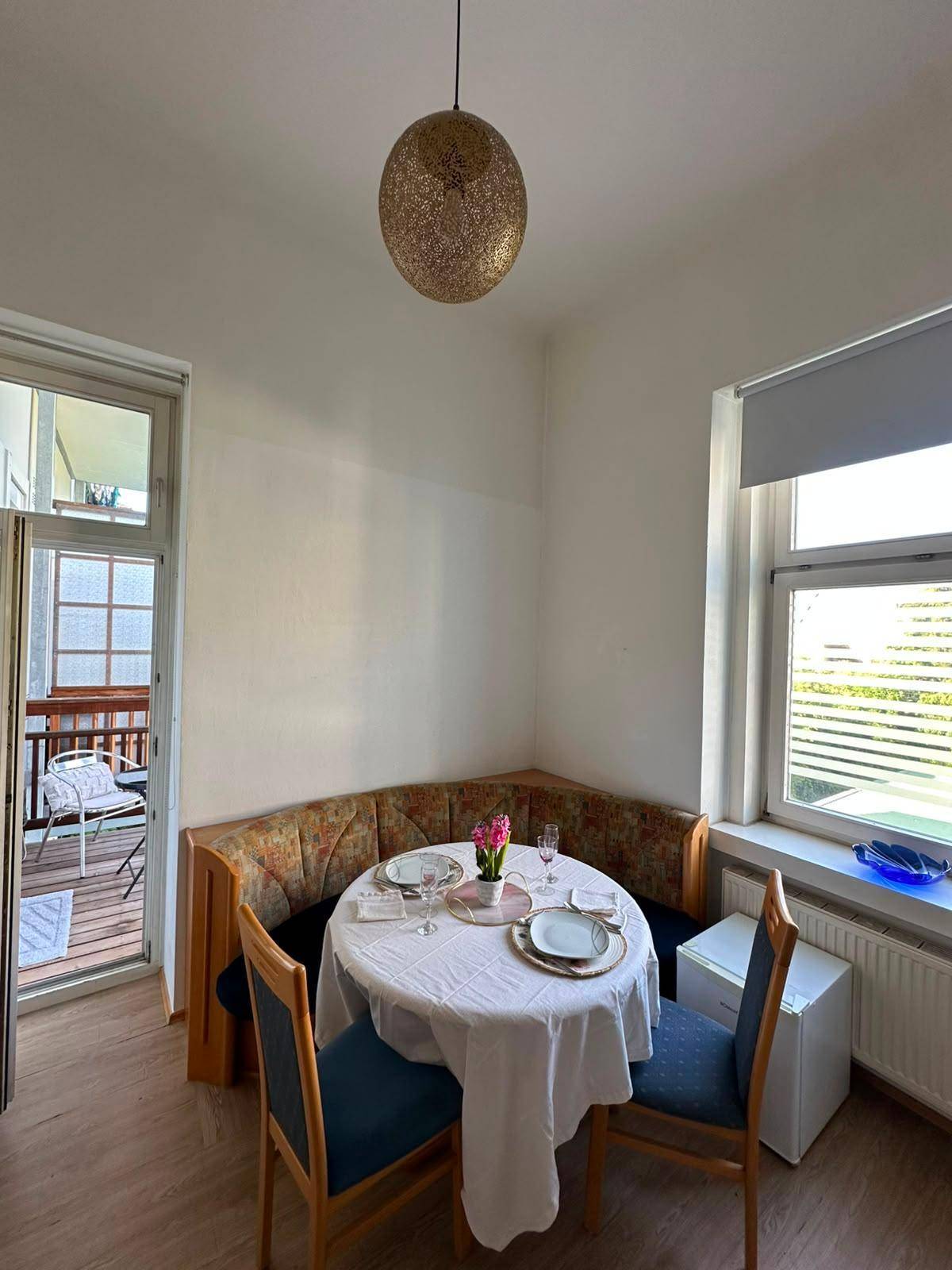 Gemütlicher Essbereich mit Eckbank, gedecktem Tisch und Zugang zu einem Balkon.