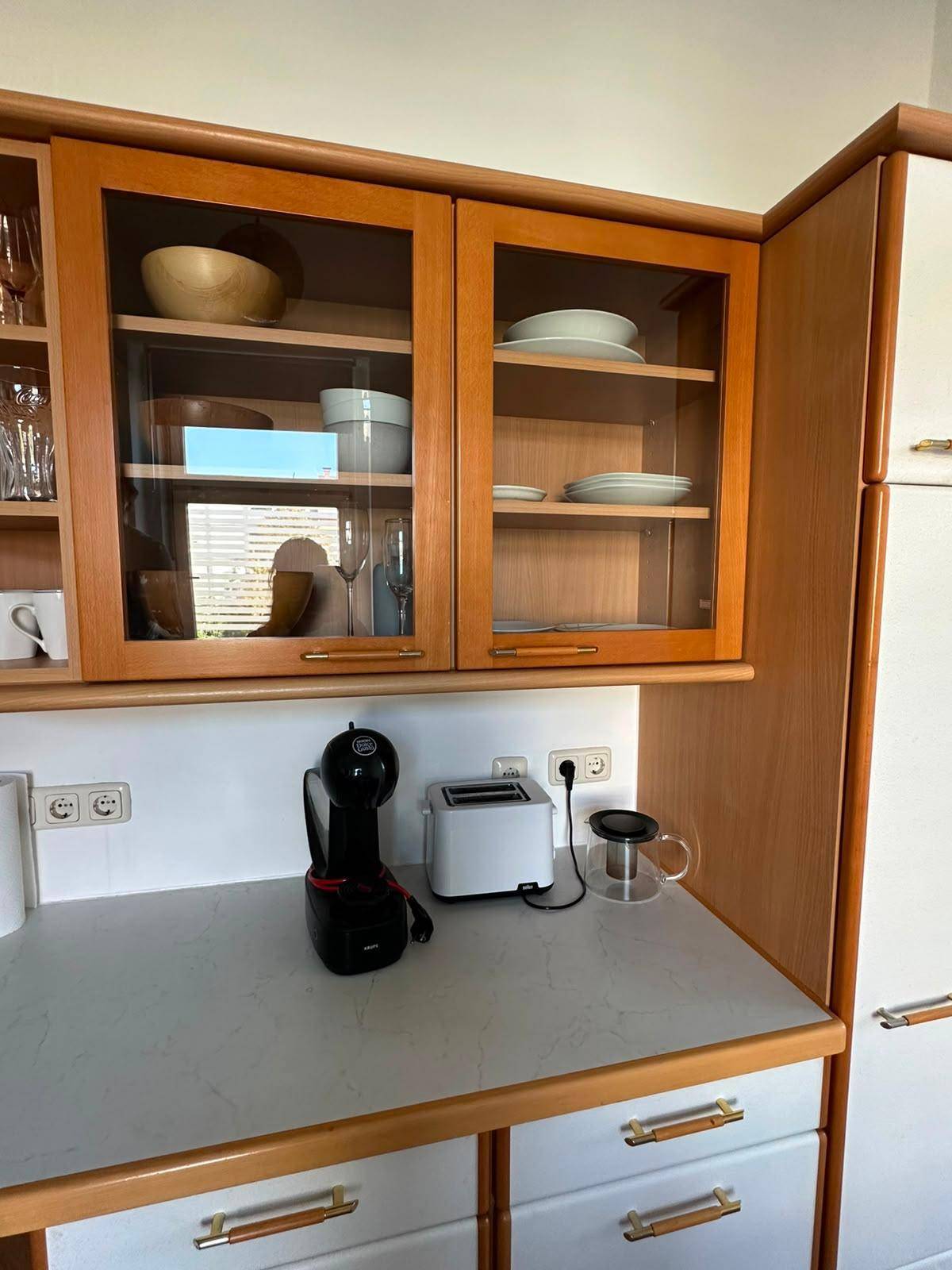 Küchenzeile mit Oberschränken, Kaffeemaschine und Toaster auf der Arbeitsplatte.