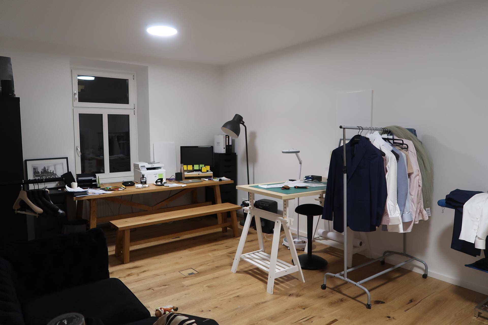 Büro- oder Arbeitszimmer mit Holztisch, Schreibtisch und Kleiderstange auf Parkettboden.
