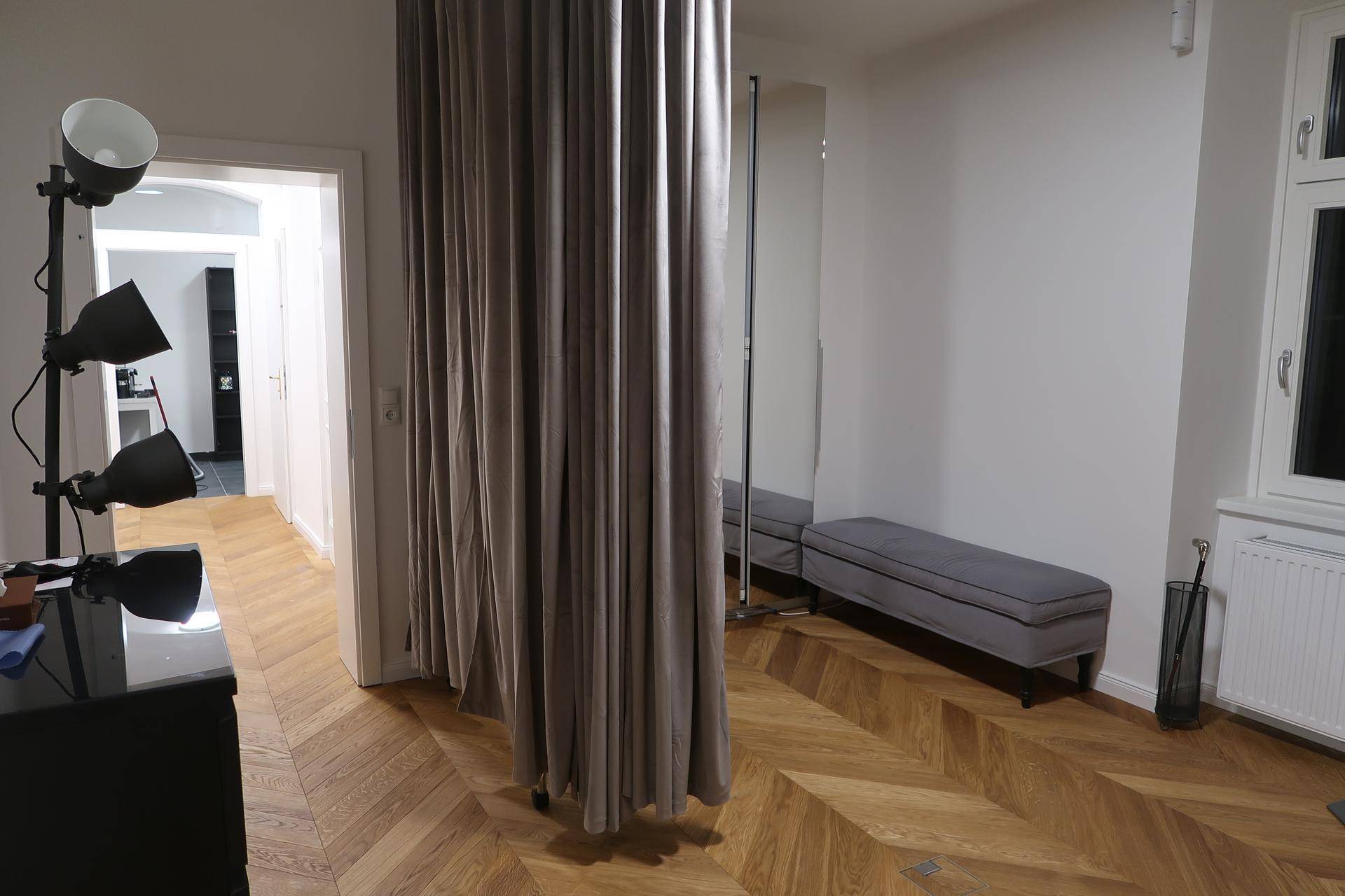 Ankleidebereich mit Vorhang als Raumteiler, Sitzbank und Fischgrätparkett.