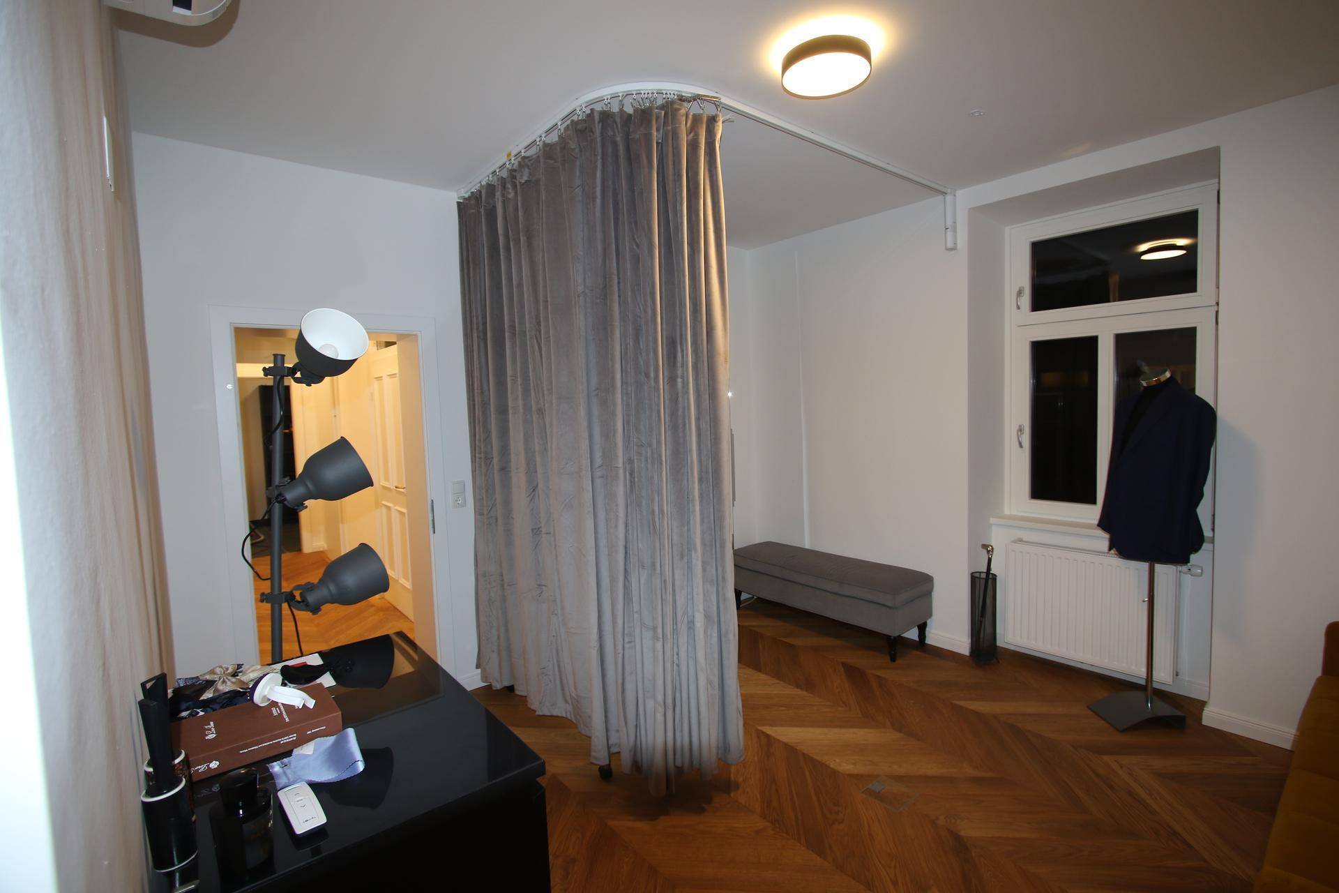 Büroraum mit Fischgrätparkett, Vorhang als Raumteiler und großem Fenster.