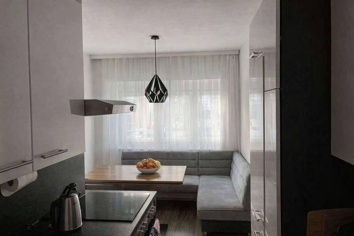 Moderne Küche mit integrierter Sitzecke, Kochfeld und Hängeleuchte am Fenster.