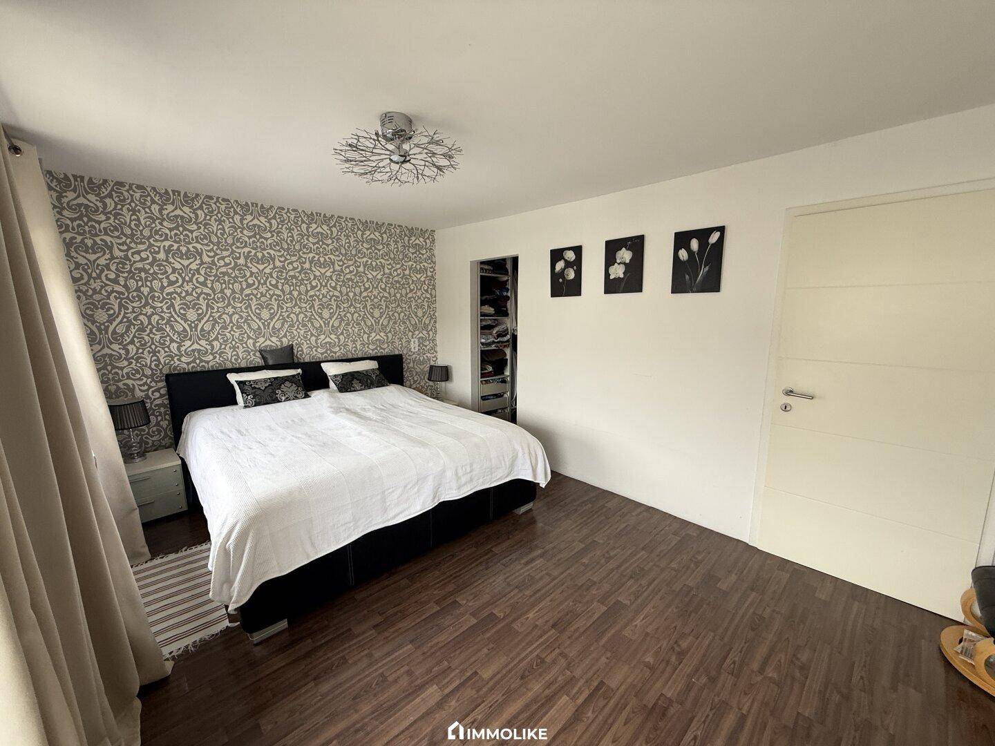 Schlafzimmer mit Laminatboden, Doppelbett und integriertem Kleiderschrankbereich.