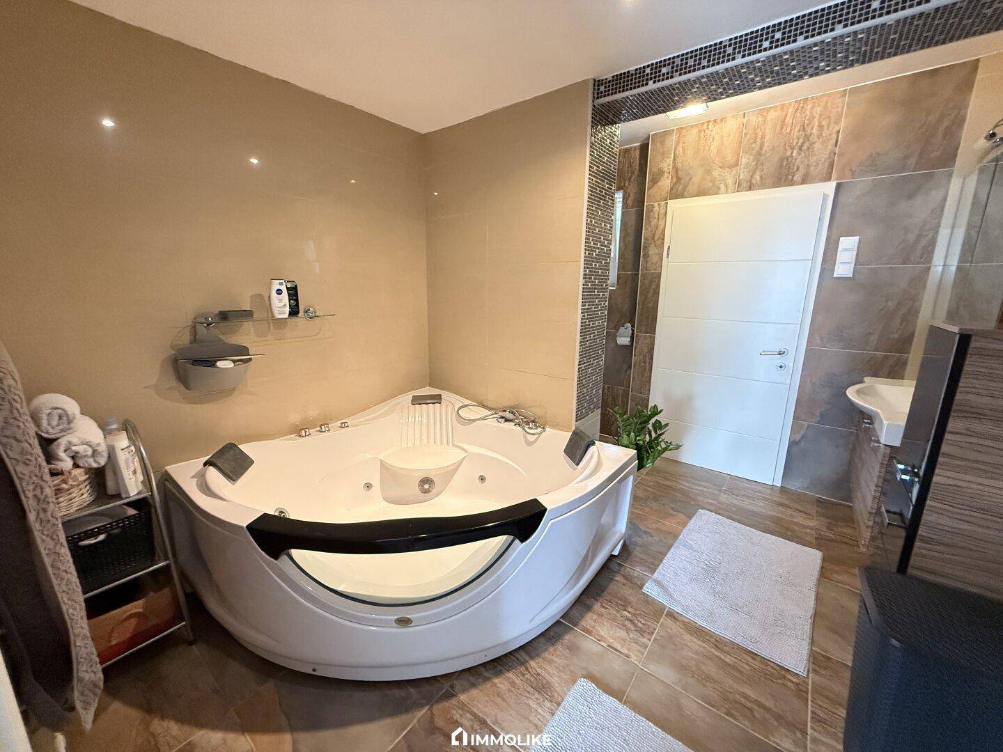 Modernes Badezimmer mit Eck-Whirlpool-Badewanne und braunen Fliesen.
