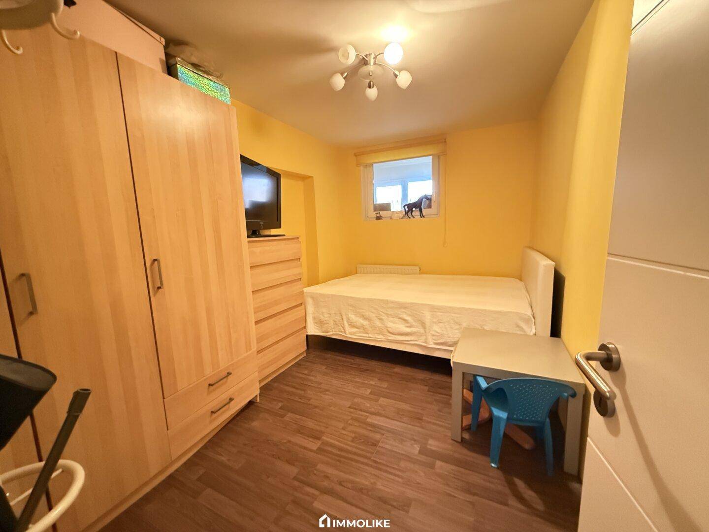 Kleines Schlafzimmer mit gelben Wänden, Laminatboden und Einzelbett.