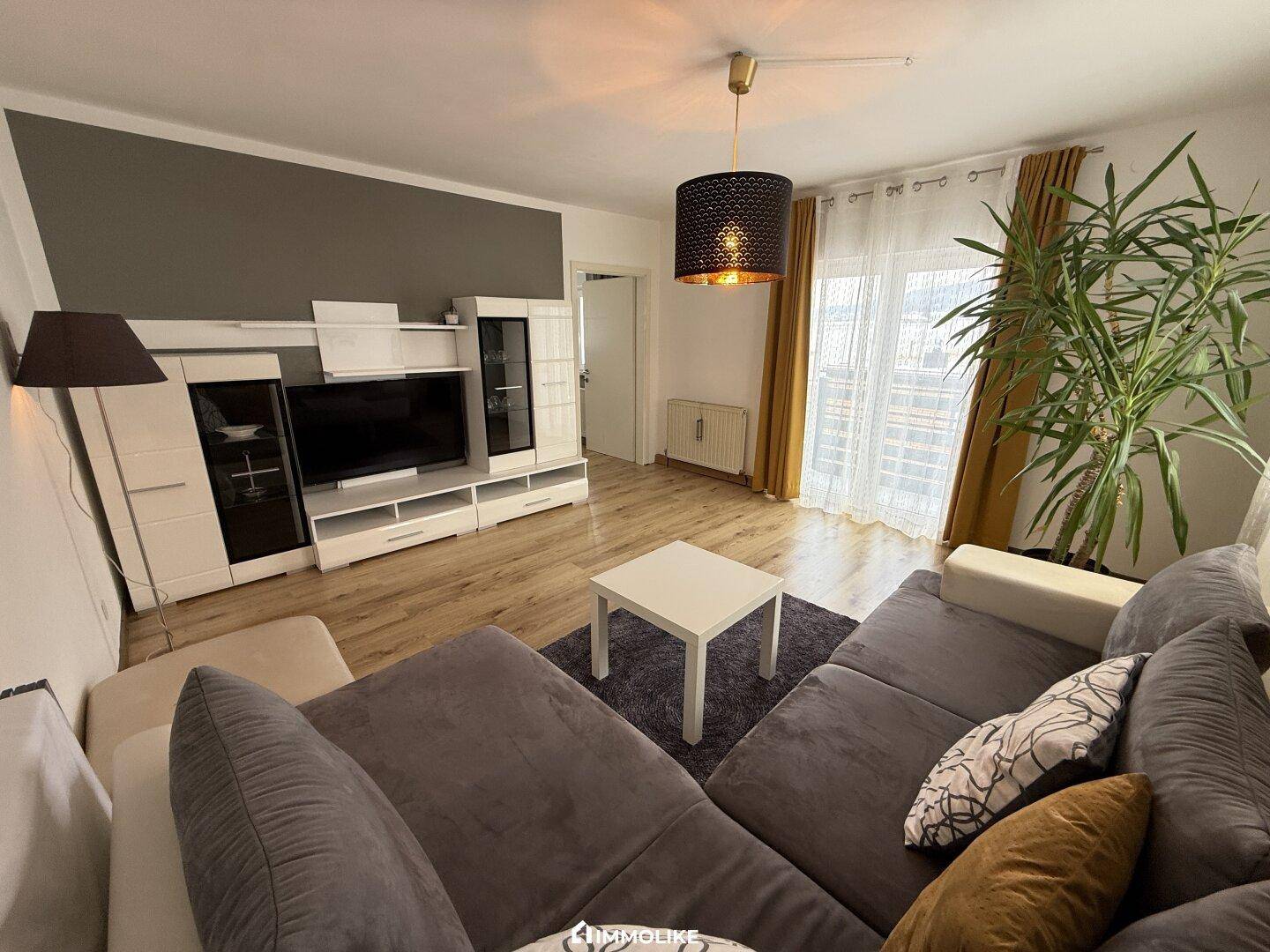 Wohnzimmer mit modernem Mediamöbel, Sofa und Blick auf den Balkon.